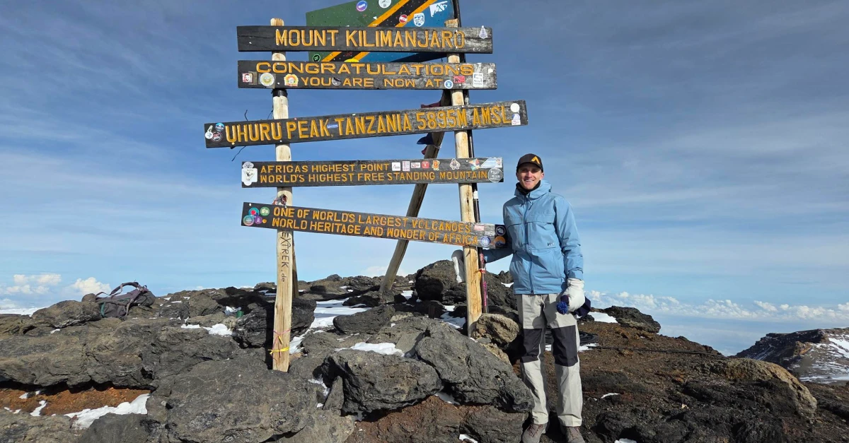 Tyler Hinytzke standing at top of mountain summit